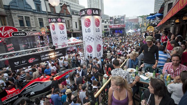 Au centre-ville de Montréal des touristes sont conviés à une série d'activités. Des voitures sont exposées en pleine rue.