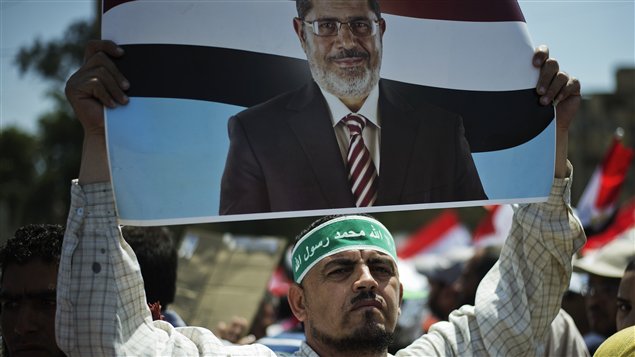 أحد المتظاهرين الداعمين للرئيس المصري محمد مرسي رافعاً صورته اليوم في القاهرة
