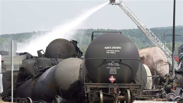 Des pompiers arrosent l'un des nombreux wagons qui a pris en feu à Lac-Mégantic. 