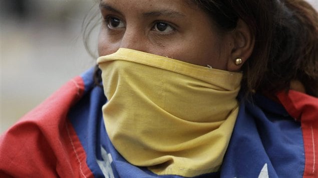 Una estudiante universitaria venezolana cubre su rostro con la bandera nacional  durante una manifestación contra el gobierno, el pasado 29 de junio, en Caracas. 