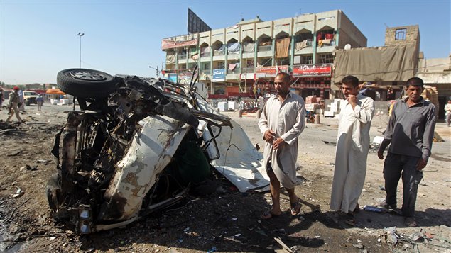 Des Iraquiens observent les restent d'une voiture qui a explosé le 29 juillet 2013 dans le quartier de Sadr City, à Baghdad
