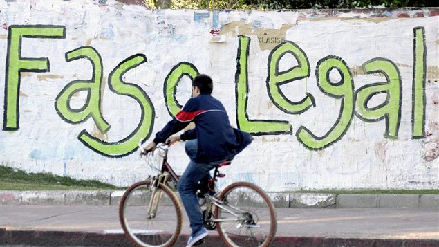 Un joven circula en bicicleta frente a una pared, de Montevideo, la capital uruguaya, en la que se lee un grafiti favorable a la legalización de la marihuana en el país.