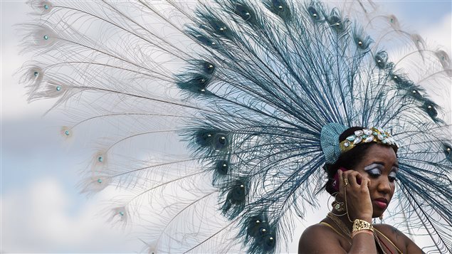 Une femme participant au Carnaval des Caraïbes de Toronto parle au téléphone.