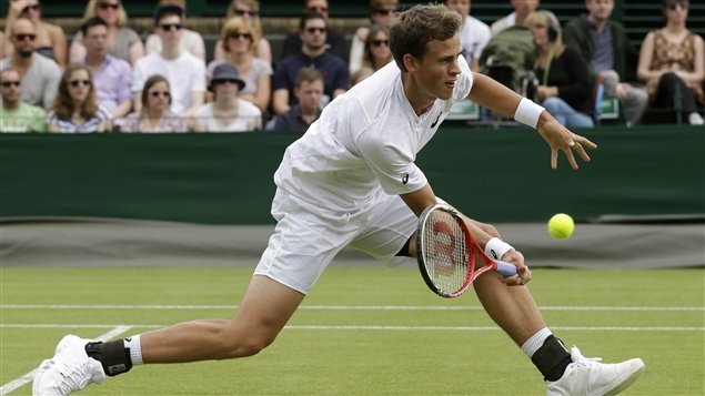 Vasek Pospisil dressed in white reaches down for a low forehand.