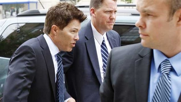 Dr. Anthony Galea surrounded by US agents and wearing a blue suit and tie hunches slightly as he heads to the court house in Buffalo, N.Y. in 2011.