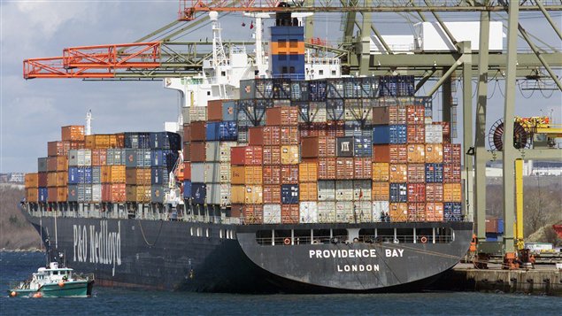 A work boat heads past a container ship loaded to the gills with boxes of cargo in calm harbour water under blue skies in Providence Bay in Halifax in 2002. A report says new systems set to replace old scanners in search of contraband is unreliable. 