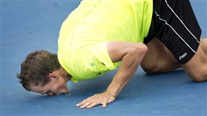 Vasek Pospisil on his knees kisses the blue court in Montreal.