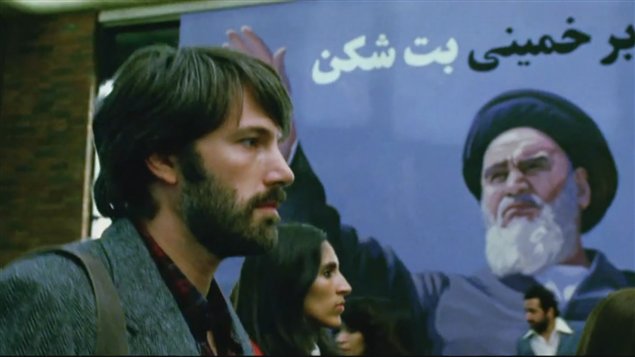Ben Affleck interpretando a Tony Méndez, el super agente de la CIA, marchando frente a una imagen del Ayatolá Jomeini.