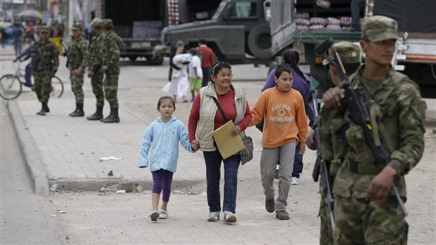 Los peatones se movilizan en medio de la vigilancia de los soldados en la localidad de Soacha al sur de Bogotá, la capital colombiana. El presidente Juan Manuel Santos ordenó la militarización para evitar los desordenes.