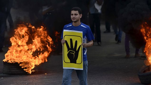 Un manifestant au Caire portant la pancarte symbolisant la répression de la place Rabia Al-Adawiya