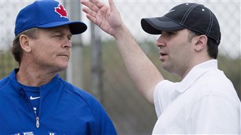 Jays general manager Alex Anthopoulos, right, talks with manager John Gibbons, left, during spring training in February when many thought the Jays would contend in the AL East. They are currently in last place, 19.5 games out of first.  Anthopoulos is wearing a scruffy baseball cap while Gibbons is in a blue warmup jacket and blue Jays cap.