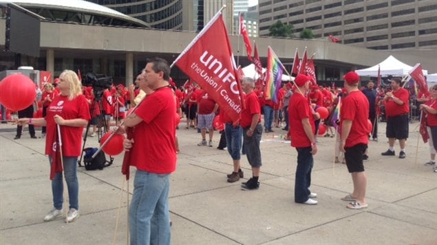 Des dizaines de membres du nouveau syndicat Unifor sont réunis devant l'hôtel de ville de Toronto, en prévision du défilé de la fête du Travail.
