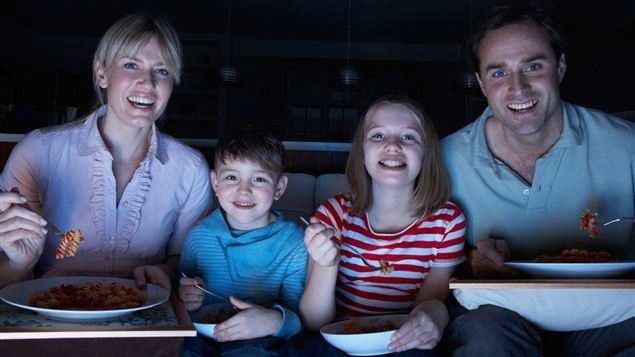 Une famille mange devant le téléviseur.