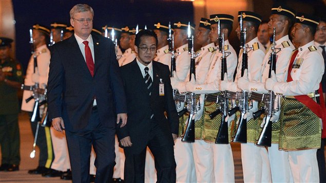 Le premier ministre Stephen Harper escorté par un fonctionnaire à son arrivée à Kuala Lumpur, en Malaisie. 