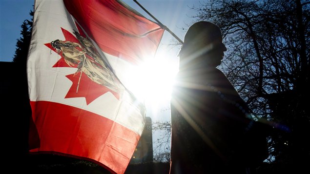 今年一月，一名原住民示威者手举加拿大国旗在温哥华市政府前示威。