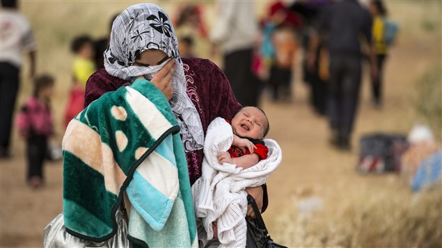 Une syrienne traverse la frontière jordanienne avec un jeune bébé. 