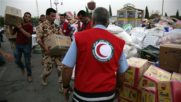 Des membres du Croissant-Rouge iraquien accumulent les produits qu'ils comptent envoyer en Syrie. 