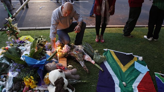 Un homme allumer une chandelle devant la maison de Nelson Mandela.