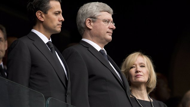 Prime Minister Stephen Harper is flanked by his wife, Laureen, on his left and Mexican President Enrique Pena Nieto Tuesday in Johannesburg during the memorial to Nelson Mandela. All three appear mournful and stern are wearing the appropriate dark clothes.