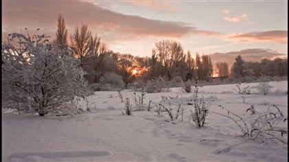 Evening fall in Wales with snow on the ground and the sun dipping below the horizon.