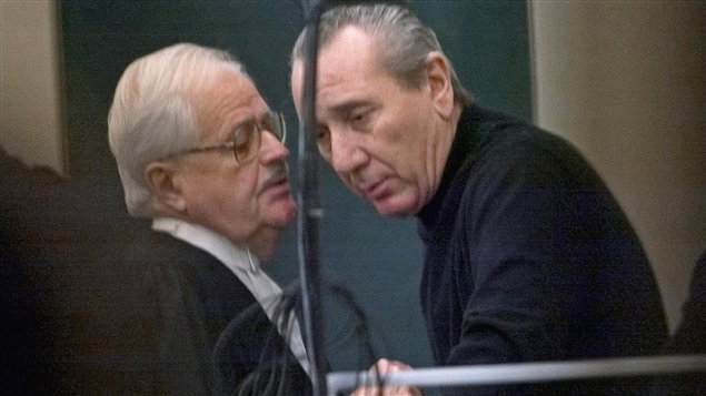 Vito Rizzuto (right) speaks with his attorney Jean Salois after his hearing in Montreal in February, 2004. Both men are wearing dark suits while Rizzuto is in the dock.