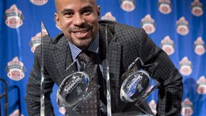 Jon Cornish, of the Calgary Stampeders, poses with his trophies for the most outstanding player and the most outstanding Canadian at the CFL Players Awards in November in Regina. Cornish also won the Lou Marsh Trophy as Canada's top male athlete. Cornish is all smiles as the trophies sit in front of him and his shaved head is aglow from the lights.