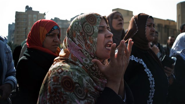 سيدة مصرية تهتف ضد الإخوان المسلمين اليوم في القاهرة فيما كان مسؤولون أمنيون يتفقدون حطام حافلة نقل عام تعرضت لهجوم بواسطة قنبلة