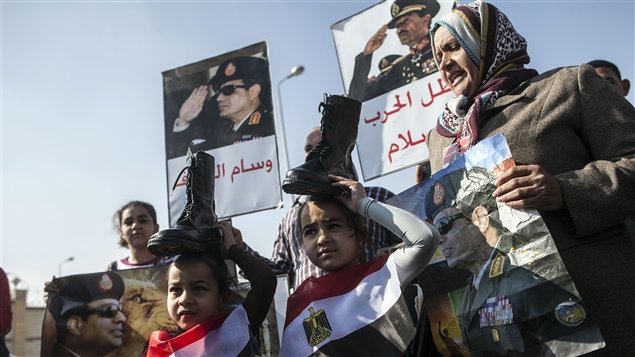 مناصرون لقائد الجيش المصري المشير عبد الفتاح السيسي يرفعون صوره وصورة الرئيس الراحل، ابن المؤسسة العسكرية أيضاً، أنور السادات "بطل الحرب والسلام" أمس في القاهرة، فيما حمل طفلان على صدريهما علم مصر ووضعا فردة حذاء عسكري على رأسيهما تعبيراً عن دعم الحكم العسكري