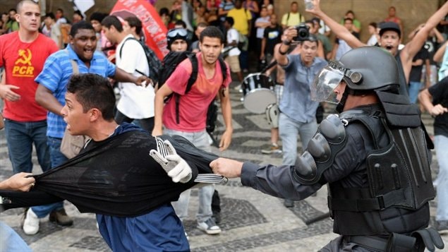 Agente del Batallón de Operaciones Especiales de la Policía tratando de detener a un joven manifestante.
