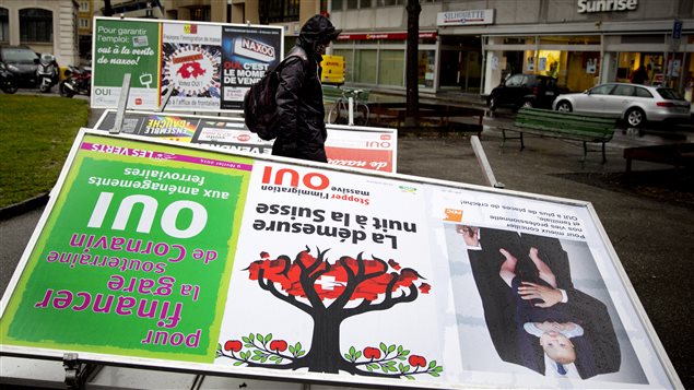 Un homme passe devant une affiche prônant l'arrêt de le l'immigration en Suisse, le 10 février 2014 