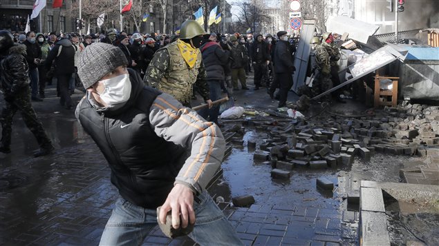 Des manifestants lancent des pavés à des policiers anti-émeute devant le parlement ukrainien, à Kiev.