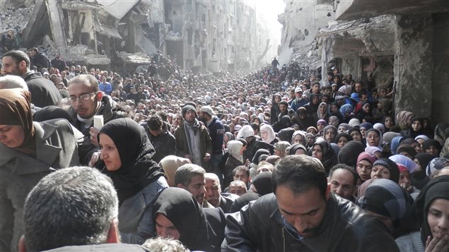 Des réfugiés du camp de Yarmouk, au sud de Damas, font la file pour recevoir de l'aide humanitaire. 