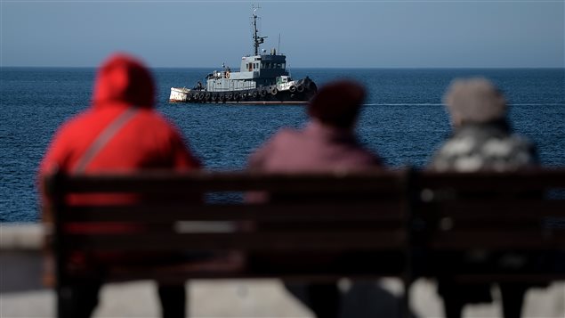 Des Ukrainiens de Crimée observe un bateau de l'armée russe près du port de Sébastopol