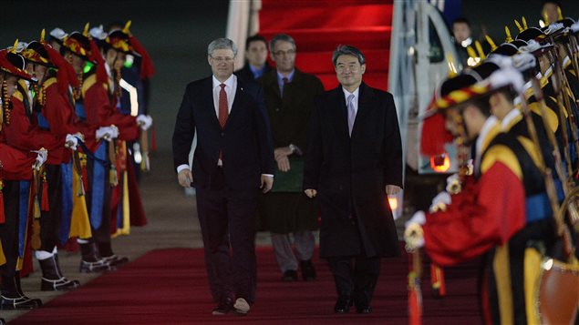 رئيس الحكومة الكندية ستيفن هاربر (إلى اليسار في وسط الصورة) عند وصوله اليوم إلى مطار سيول العسكري وإلى جانبه النائب الأول لوزير خارجية كوريا الجنوبية، تشو تاي يونغ