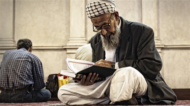 Un vieil homme lit le Coran assis en indien