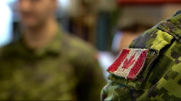 Un soldat porte l'uniforme avec le drapeau canadien sur l'épaulette, à la base d'Edmonton, le 6 mars 2014.
