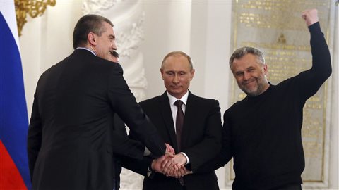 Le prédisent russe, Vladimkir Poutine, scelle par une poignée de main l'accord sur l'annexion de la Crimée avec les premier ministre de Crimée, Sergeï Aksyonov (gauche) et le maire de Sébastopol, Alexei Chaliy (droite).  Mars 2014.