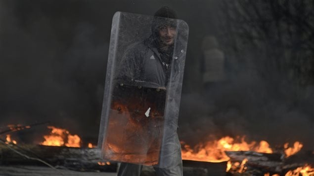 Un militant prorusse tient un bouclier devant un barrage de pneus en feu, à Slaviansk où les forces de sécurité ukrainiennes ont lancé une opération antiterroriste. 