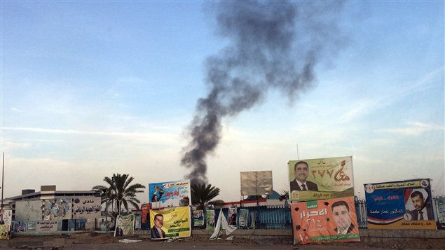 الدخان يتصاعد اليوم في سماء بغداد فوق ملصقات دعائية لمرشحين للانتخابات عقب التفجيرات التي استهدفت تجمعاً لـ"عصائب أهل الحق"