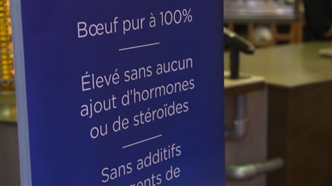 Photo : dans un supermarché, un grand écriteau bleu écrit : Boeuf pur à 100%. Élevé sans aucun ajout d'hormones ou de stéroïdes. Sans additifs...