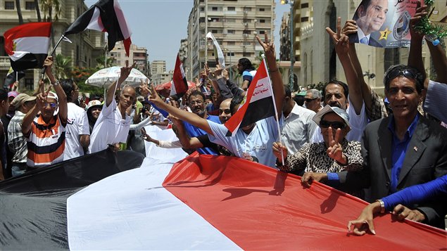 مواطنون مصريون يحملون علما مصريا ضخما يحتفلون بفوز المشير عبد الفتّاح السيسي في الانتخابات الرئاسيّة