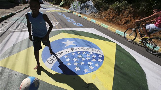 فتى يقذف الكرة فوق رسم جداري يمثّل لعبة كرة القدم في مانغاراتيبا في البرازيل في 12 حزيران يونيو 2014