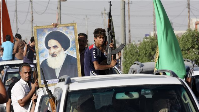 متطوعون عراقيون يرفعون صورة المرجع الشيعي آية الله علي السيستاني نهاية الأسبوع الفائت عقب توجيهه دعوة لمواطنيه لحمل السلاح ومقاتلة "الإرهابيين"