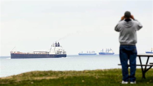 A man watches as a freighter sails on Lake Huron.