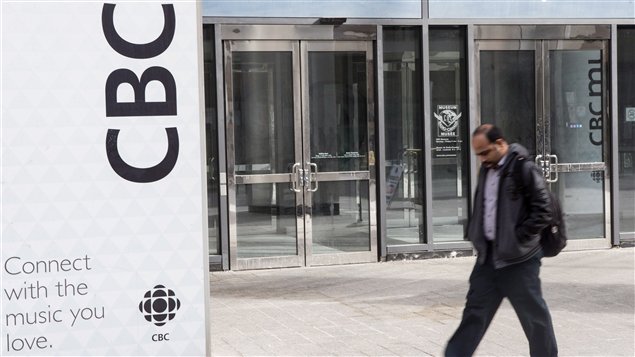 A downtrodden man shuffles by the front doors of the CBC building in Toronto, where staff cuts will see a downsizing of the work force.