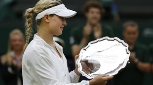 Eugenie Bouchard holds up her runners-up trophy after her defeat at Wimbledon on Saturday. She appears somewhat glum.