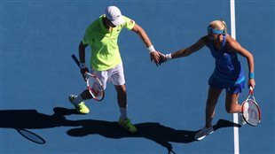 Daniel Nestor in yellow and Kristina Mladenovic of France in a blue dress grab hands after winning a point at the Australian Open mixed doubles championship earlier this year.