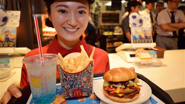 Une employée de McDonald au Japon montre le menu spécial FIFA