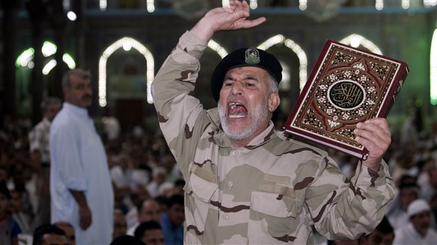 مقاتل شيعي عراقي يردد شعارات مناهضة لتنظيم "الدولة الإسلامية" السني المتطرف وبيده المصحف خلال صلاة يوم الجمعة الفائت في أحد مساجد كربلاء 