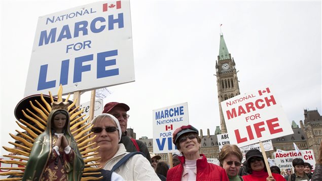 The battle between those who support abortion and those against it continue to spar across Canada. Here, anti-abortion activists march off of Parliament Hill in Ottawa in 2010. In the photo, we see the Peace Tower in the background. In the foreground are mainly women holding signs that say "March for Life." One woman is holding what appears to be two or three foot statue of the Virgina Mary.